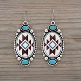 Pair of earrings with geometric pattern and turquoise stones on a white background
