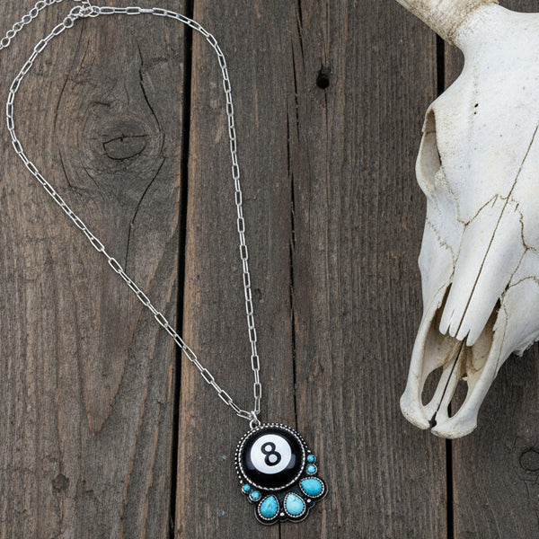 Necklace with a circular pendant featuring the number 8 and turquoise stones on a light gray background.